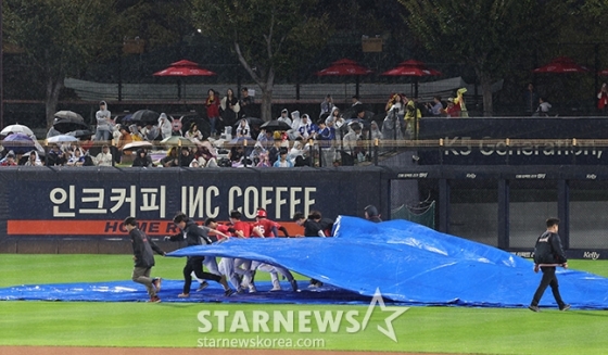 경기장 스태프들이 구장에 내린 비로 방수포를 덮고 있다. /사진=김진경 대기자