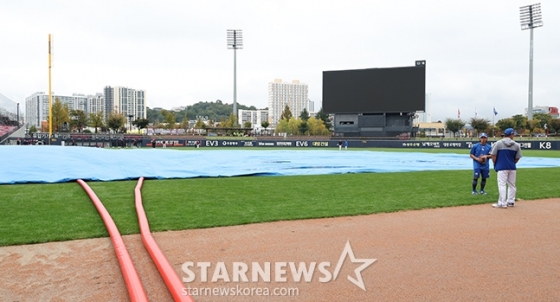 '2024 KBO 포스트시즌 한국시리즈 1차전' KIA-삼성전 서스펜디드 경기가 22일 광주-기아챔피언스필드에서 열렸다.  구단 관계자들이 비에 젖은 그라운드를 정비하는 가운데 KIA 선수들이 외야에서 훈련을 하고 있다. /사진=김진경 대기자