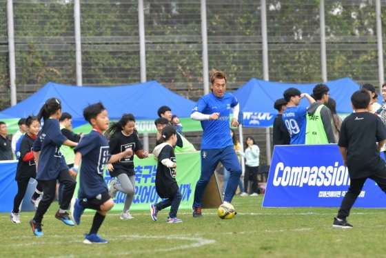 김병지(오른쪽)가 축구교실에 참여한 어린이들과 함께 드리블을 하고 있다. /사진=한국컴패션 제공