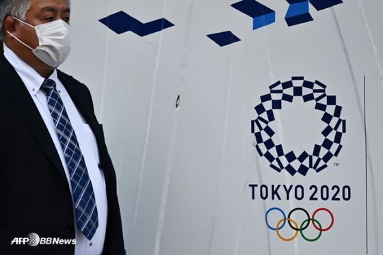 한 관계자가 도쿄 올림픽 마크 앞을 지나고 있다. /AFPBBNews=뉴스1