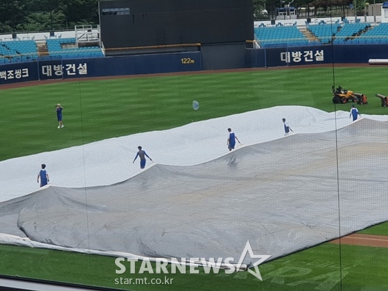 삼성 라이온즈파크 관계자들이 대형 방수포를 걷고 경기 준비에 들어갔다. /사진=이원희 기자