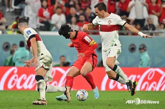 손흥민(가운데)이 3일 열린 2022 카타르 월드컵 H조 한국-포르투갈전에서 포르투갈 선수들을 제치고 드리블을 하고 있다. /AFPBBNews=뉴스1