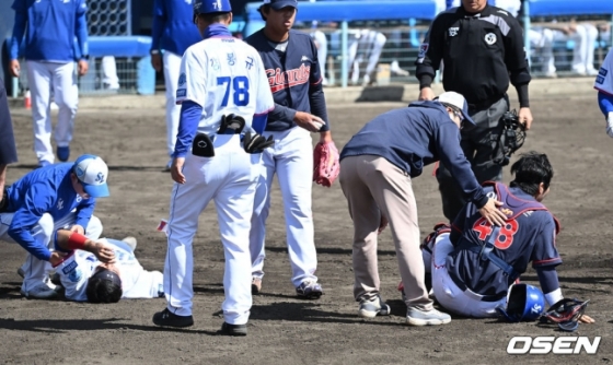 삼성 김태군(왼쪽 2번째)이 지난달 28일 일본 오키나와현 온나손 아카마 볼파크에서 열린 롯데와 연습경기에서 주루 도중 포수와 충돌해 고통을 호소하고 있다.