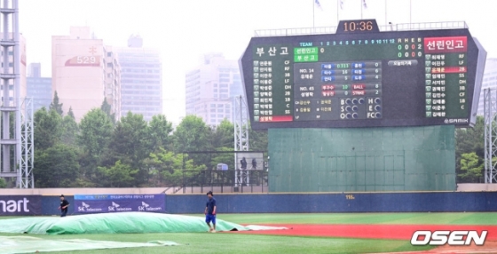  27일 서울 목동야구장에서 ‘제77회 황금사자기 전국고교야구대회 겸 주말리그 왕중왕전’ 결승 부산고와 선린인터넷고등학교의 경기가 열렸다. 1회초 무사 2루 상황에서 우천으로 경기가 중단됐다. 경기 진행요원들이 그라운드에 방수포를 설치하고 있다. 