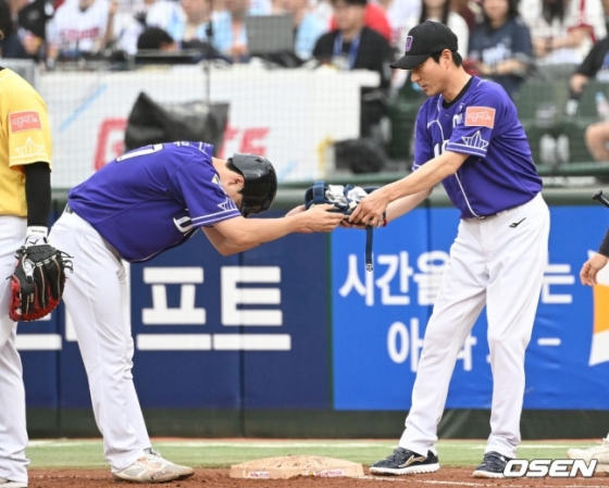 나눔 올스타 박건우(NC)가 15일 부산 사직야구장에서 열린 2023 KBO 올스타전에서 1회말 안타를 치고 나간 뒤 강인권(NC) 1루 코치에게 90도 고개를 숙이며 장비를 전달하고 있다.