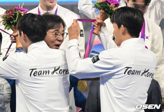 정우영(오른쪽)이 자신의 금메달을 황 감독에게 걸어주고 있다.