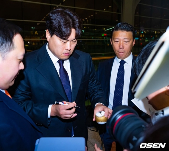 류현진(가운데)이 인천국제공항에 자신을 보기 위해 찾아온 팬에게 사인을 해주고 있다.