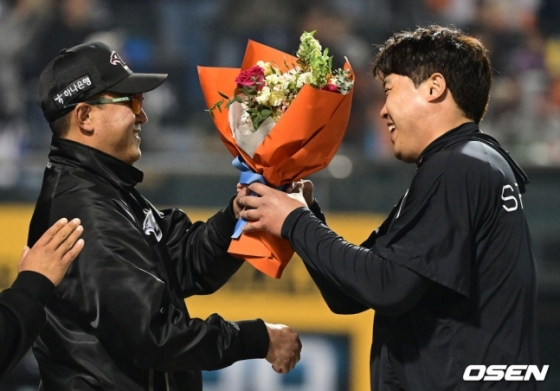류현진(왼쪽)이 30일 대전 SSG전에서 KBO 리그 통산 100승을 달성하고 최원호 감독으로부터 꽃다발을 받고 있다. 