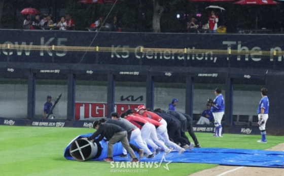 &#039;2024 KBO 포스트시즌 한국시리즈 1차전&#039; KIA-삼성전이 21일 광주-기아챔피언스필드에서 열리기에 앞서 비가 쏟아지자 경기준비요원들이 대형 방수포으로 그라운드를 덮고 있다. /사진=김진경 대기자