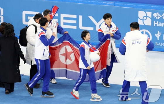 북한 렴대옥·한금철이 12일 중국 헤이룽장성 하얼빈 빙상훈련센터 다목적홀에서 열린 시상식을 마치고 인공기를 펼치고 있다. /사진=뉴스1