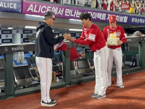SSG 감독으로 100번쨰 승리를 수확한 이숭용 감독(왼쪽)에게 김광현이 기념구와 최정이 케이크를 선물하려고 하고 있다.  /사진=SSG 랜더스
