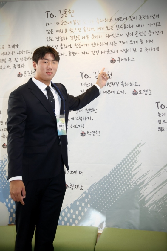 KT 김동현이 27일 수원KT위즈파크에서 열린 2025 신인선수 초청 행사를 앞두고 선배들의 응원 메시지 앞에서 사진을 찍고 있다. /사진=KT 위즈 제공