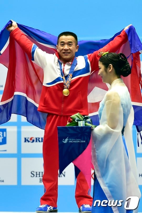 북한 역도 대표팀의 엄윤철이 20일 오후 인천 달빛축제공원 역도경기장에서 열린 '2014 아시안게임' 역도 남자 56kg A그룹 경기에서 첫 금메달을 획득한 뒤 시상대 위에서 환한 표정으로 관중석을 향해 인사하고 있다. /사진=뉴스1