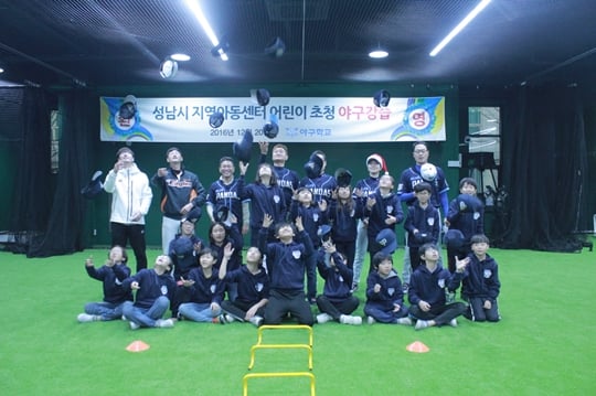 성남시 관내 지역아동센터 어린이들이 야구강습 행사를 마친 뒤 모자를 높이 던지며 지도해 준 야구학교 코치진과 기념촬영을 하고 있다./사진=스포츠투아이 제공