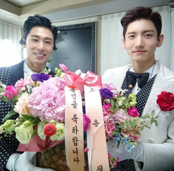 동방신기가 선배가수 조용필이 보낸 꽃바구니를 들고 웃고 있다.