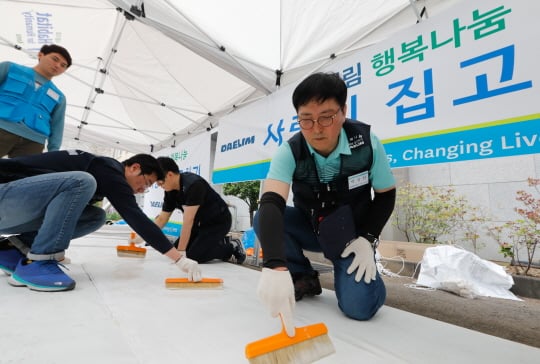 대림산업 박상신 대표(우측 첫번째)가 도배작업에 사용할 벽지에 풀칠을 하고 있다./사진제공=대림