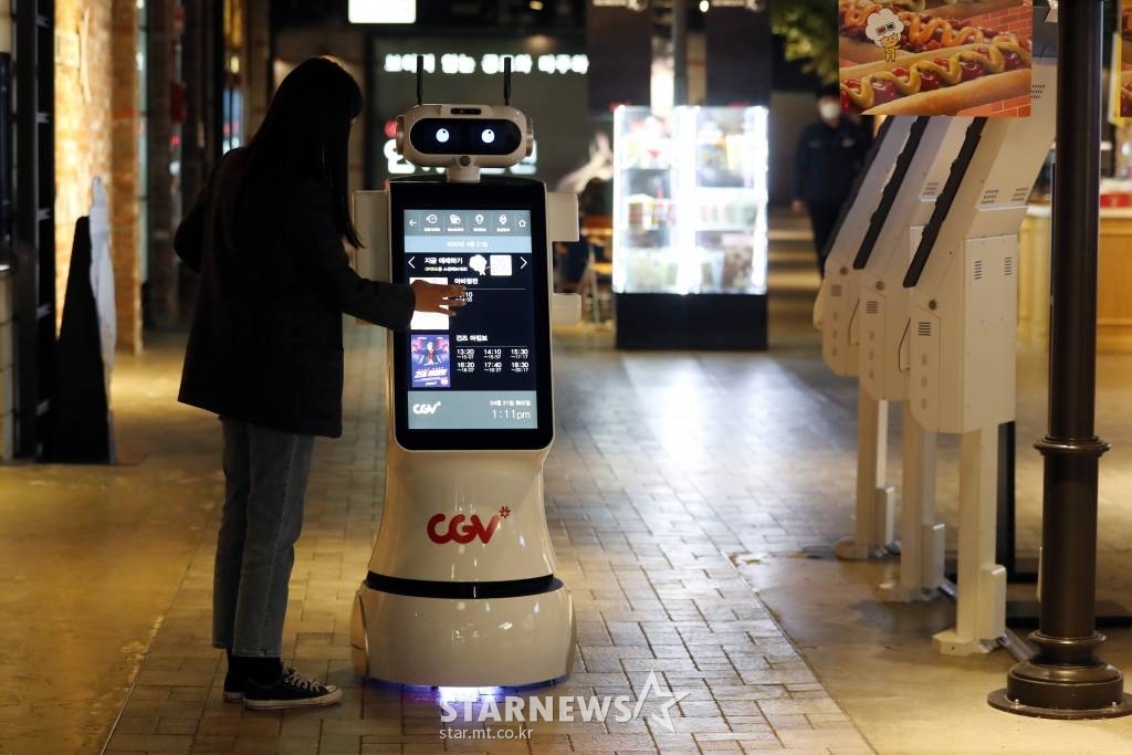 CJ CGV가 대면 서비스를 최소화한 '언택트시네마'를 선보인 가운데 21일 서울 CGV 여의도에서 한 시민이 자율주행 로봇 체크봇을 이용해 상영관 위치를 찾고 있다. '언택트시네마'는 다양한 하이테크 기술을 통해 언택트(Un-tact) 서비스를 기반으로 새롭고 간편하게 극장 시설을 이용할 수 있는 서비스다. /사진=이기범 기자 leekb@