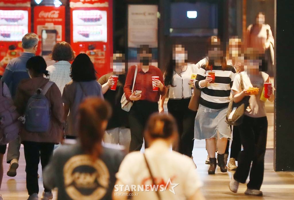 정부가 코로나19 확산 방지를 위해 금지해왔던 실내 다중이용시설 취식을 허용된 가운데 26일 오후 서울 용산구 한 영화관에서 관람객들이 음료와 먹거리를 들고 상영관으로 이동하고 있다. /사진=이동훈 기자 photoguy@
