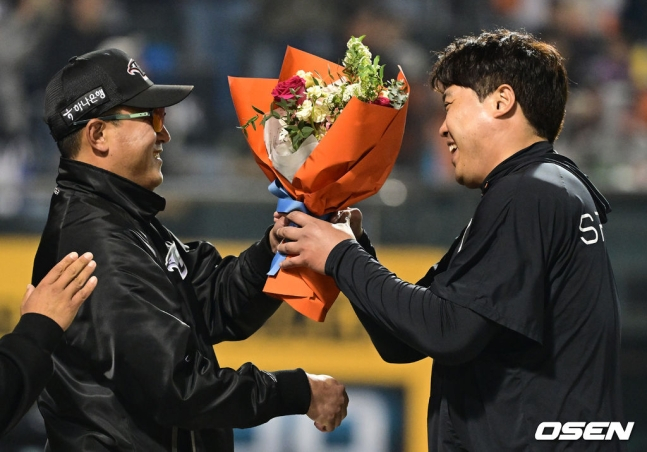 류현진(왼쪽)이 30일 대전 SSG전에서 KBO 리그 통산 100승을 달성하고 최원호 감독으로부터 꽃다발을 받고 있다.