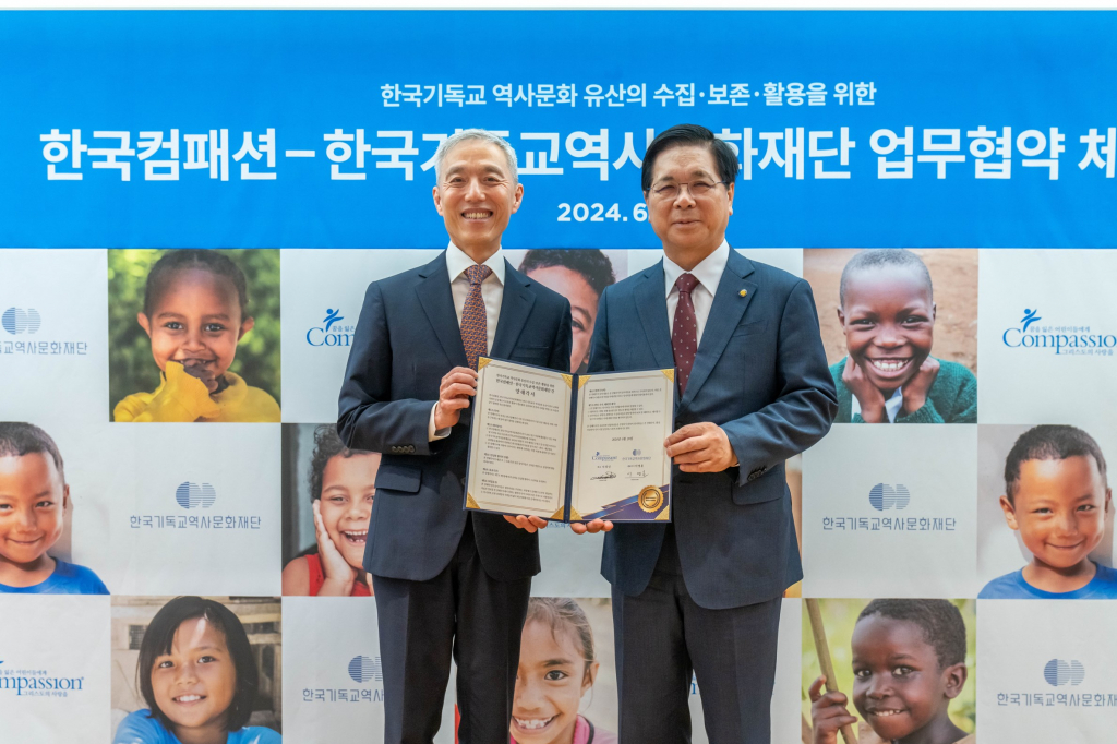 한국컴패션 대표 서정인 목사(좌), 한국기독교역사문화재단 이사장 이영훈 목사(우)가 함께 양해각서를 들고 환하게 웃고 있다