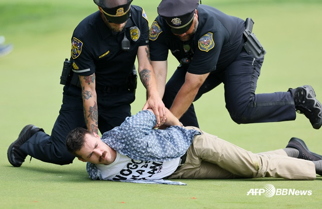 24일(한국시간) 열린 PGA 투어 트래블러스 챔피언십 4라운드 18번 홀에서 환경운동가(맨 아래)가 시위에 나서자 경찰이 진압하고 있다. /AFPBBNews=뉴스1