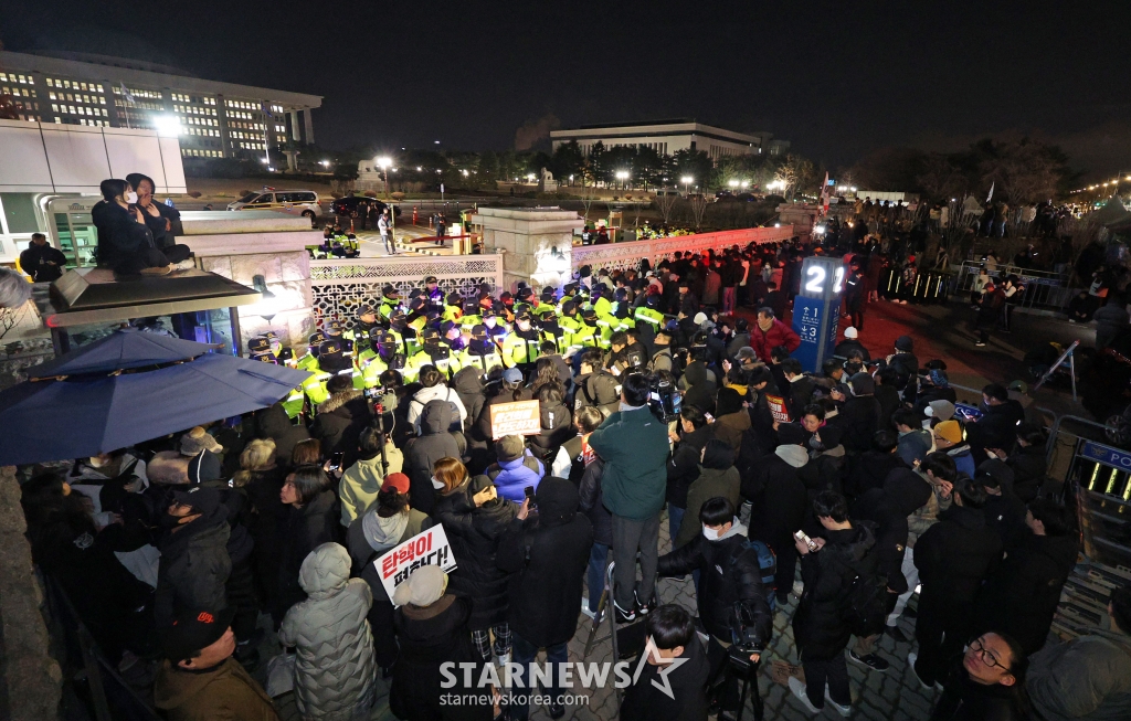 (서울=뉴스1) 장수영 기자 = 윤석열 대통령의 비상계엄 해제 요구 결의안이 국회 본회의에서 통과된 4일 새벽 서울 여의도 국회 정문 앞에 모인 시민들이 윤 대통령을 규탄하고 있다. 여야는 이날 본회의에서 재석 190명 중 찬성 190명으로 비상계엄 해제 요구 결의안을 가결 처리했다. 이에 따라 계엄령 선포는 무효가 됐다고 국회의장실은 설명했다. 2024.12.4/뉴스1 Copyright (C) 뉴스1. All rights reserved. 무단 전재 및 재배포, AI학습 이용 금지. /사진=(서울=뉴스1) 장수영 기자