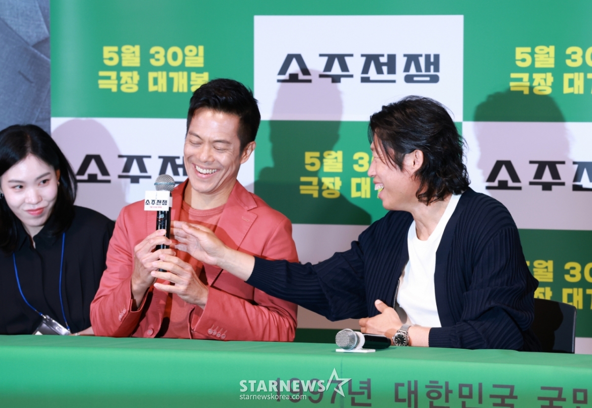 배우 유해진이 29일 오후 서울 CGV용산아이파크몰에서 진행된 영화 '소주전쟁' 언론배급시사회 및 기자간담회에서 바이런 만의 마이크를 바로잡아주고 있다. 1997년 IMF 외환위기, 소주 회사가 곧 인생인 재무이사 종록과 오로지 성과만 추구하는 글로벌 투자사 직원 인범이 대한민국 국민 소주의 운명을 걸고 맞서는 이야기 '소주전쟁'은 오는 30일 개봉한다. /2025.05.29 /사진=이동훈 photoguy@