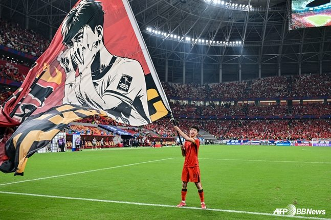 왕위동이 10일(한국시간) 중국 충칭의 롱싱 축구 경기장에서 열린 2026 국제축구연맹(FIFA) 북중미월드컵 3차 예선 최종전 바레인과 경기가 끝난 뒤 서포터가 선물한 깃발을 펄럭이고 있다. /AFPBBNews=뉴스1