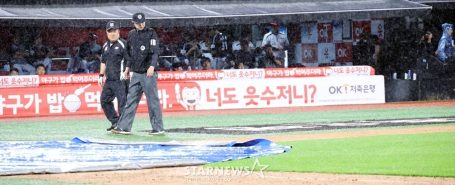 24일 수원KT위즈파크에서 열린 2025KBO리그 LG트윈스와 KT위즈의 경기에서 폭우가 쏟아져 6회초 수비를 마치고 경기가 중단된 가운데 그라운드 사정을 살피는 심판과 그라운드 관리소장. /사진=강영조 선임기자