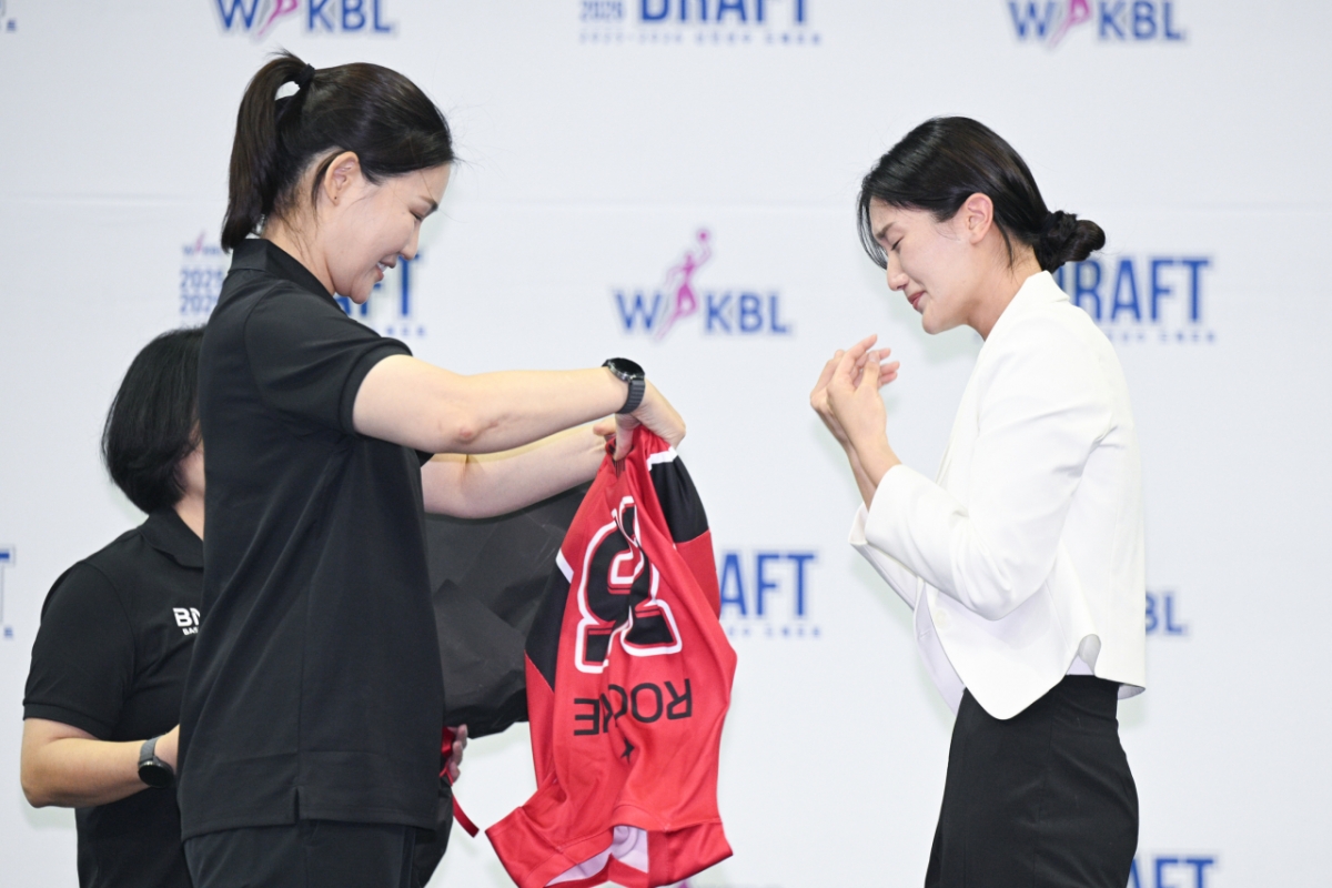 박지수(오른쪽)가 박은정 BNK 감독으로부터 유니폼을 전달받고 있다. /사진=WKBL 제공