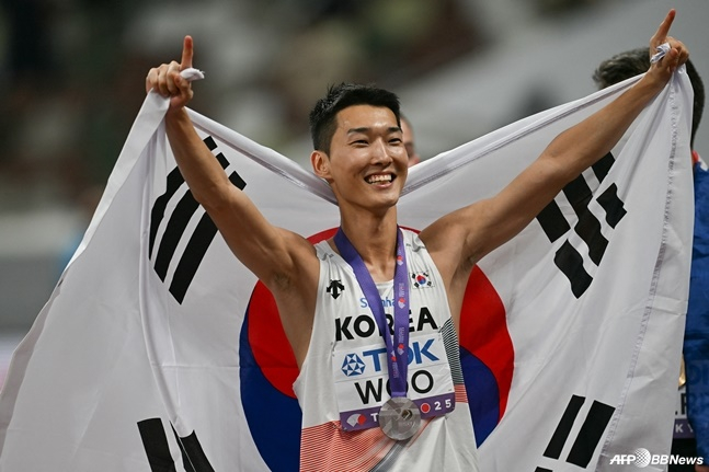 우상혁이 16일 일본 도쿄 국립경기장에서 열린 '2025 도쿄 세계육상선수권' 남자 높이뛰기 결선에서 은메달을 차지한 뒤 태극기를 펼쳐보이고 있다. /AFPBBNews=뉴스1